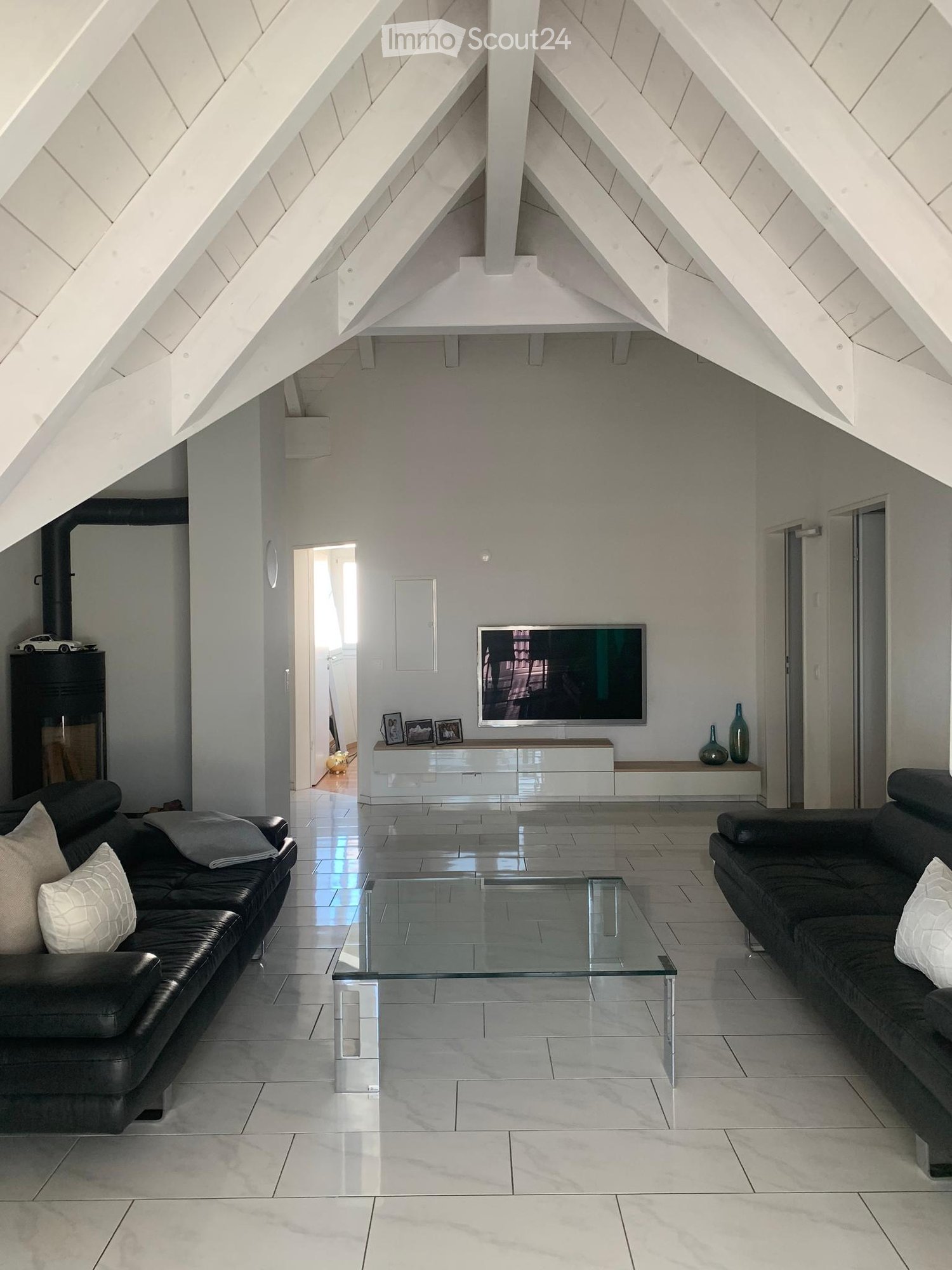 white ceiling, white tiles, black couches, TV, coffee table, fireplace