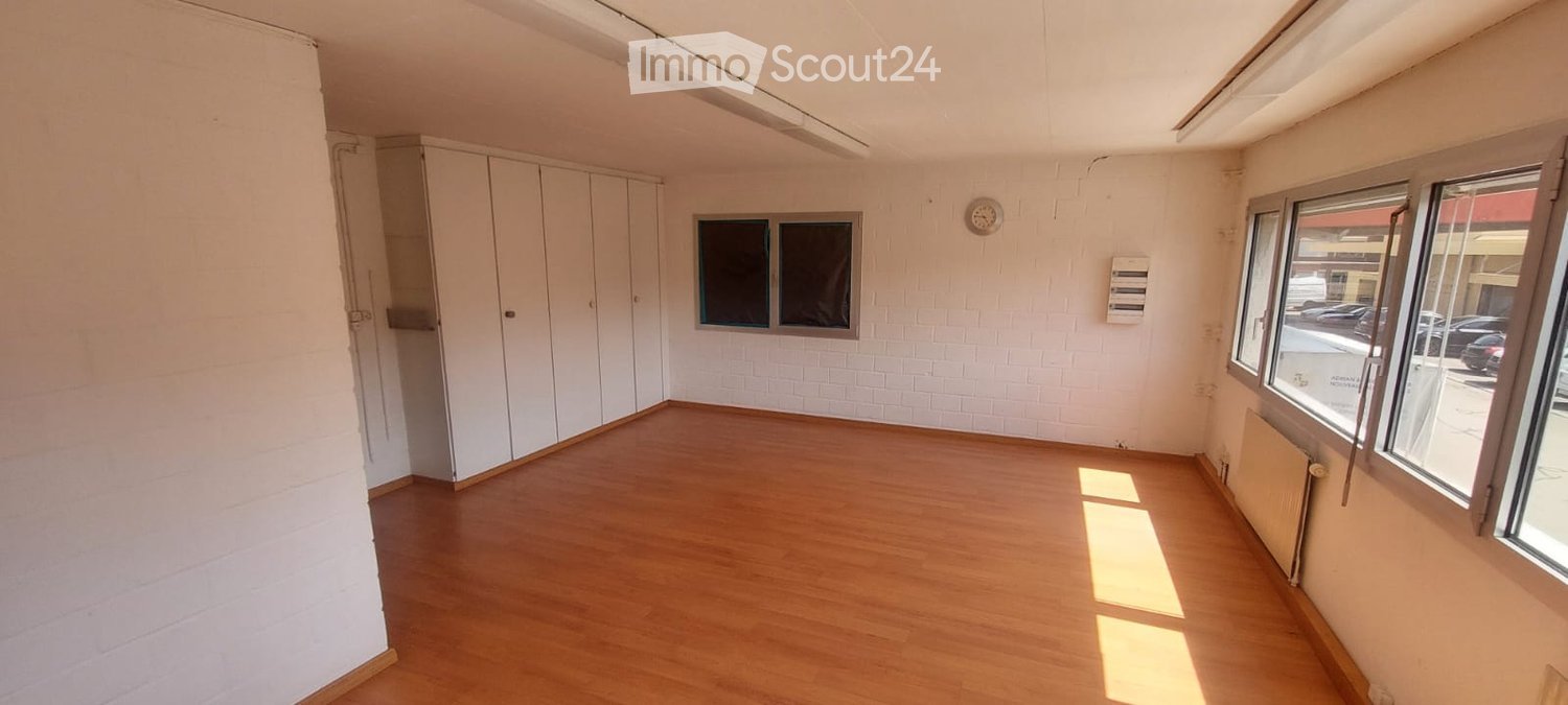 Empty room with wooden flooring, white walls, built-in wardrobes, and large windows allowing natural light.