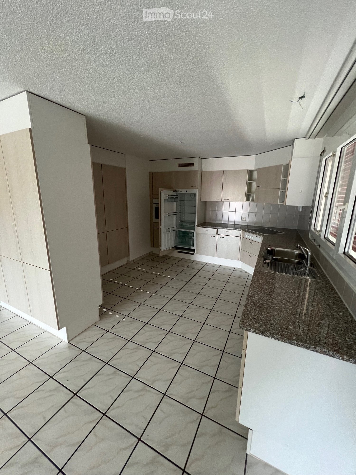Modern kitchen with white cabinets, granite countertop, tiled floor, and stainless steel sink.