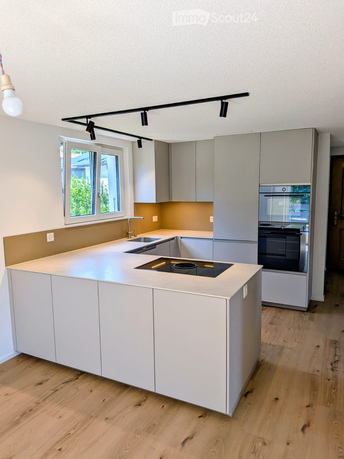 Modern kitchen with white cabinets, a central island, and built-in appliances including a sink, faucet, and oven. The island features a countertop with an integrated induction cooktop and sink area.