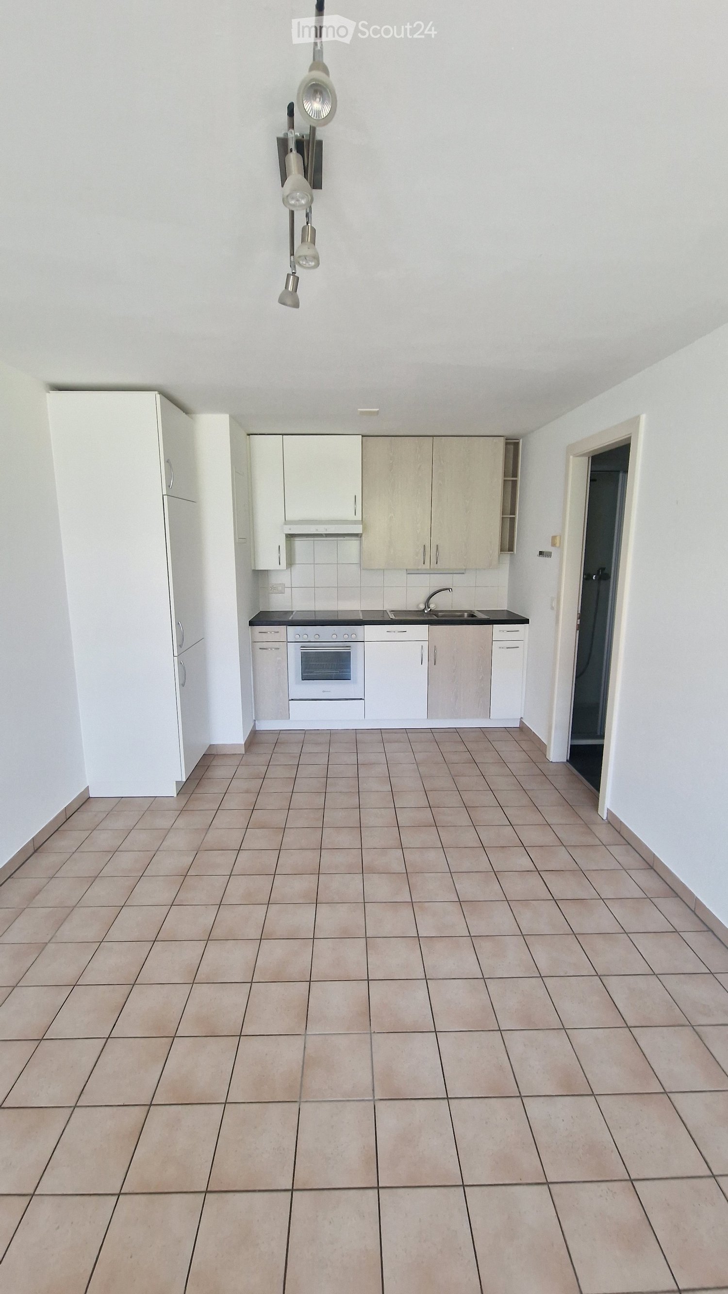 Empty kitchen with white cabinets, tiled floor, and built-in appliances including an oven and sink.