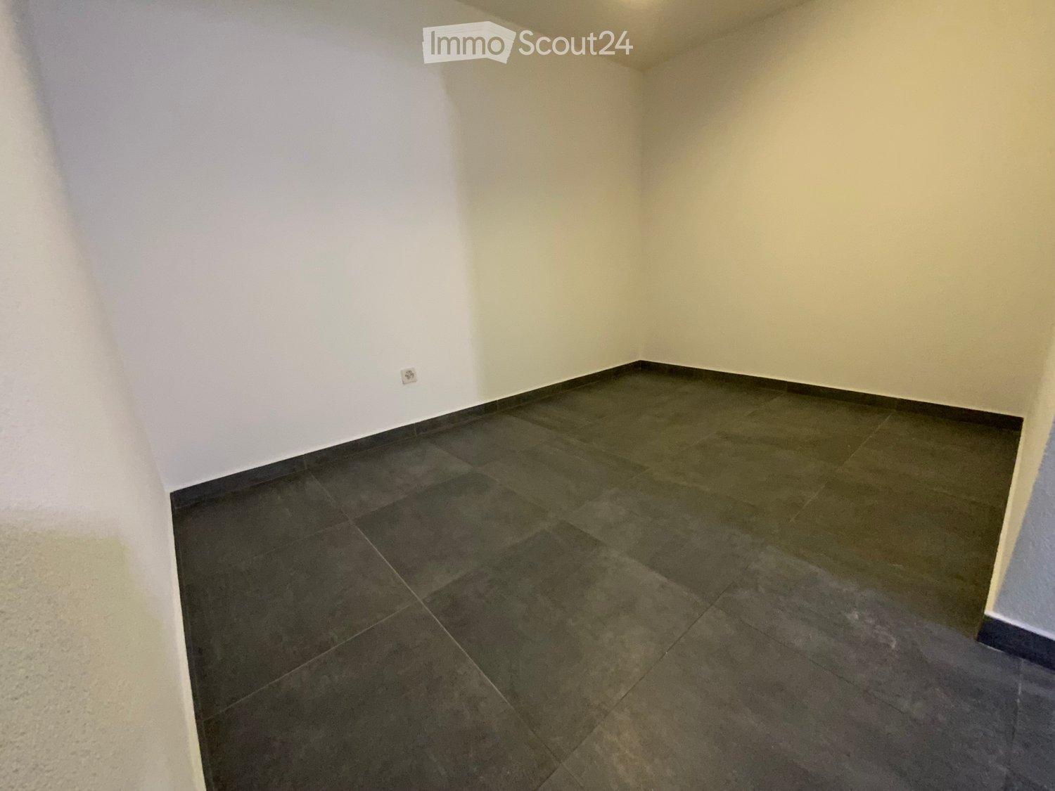 Empty room with dark tiled floor and light-colored walls, no furniture or equipment present.