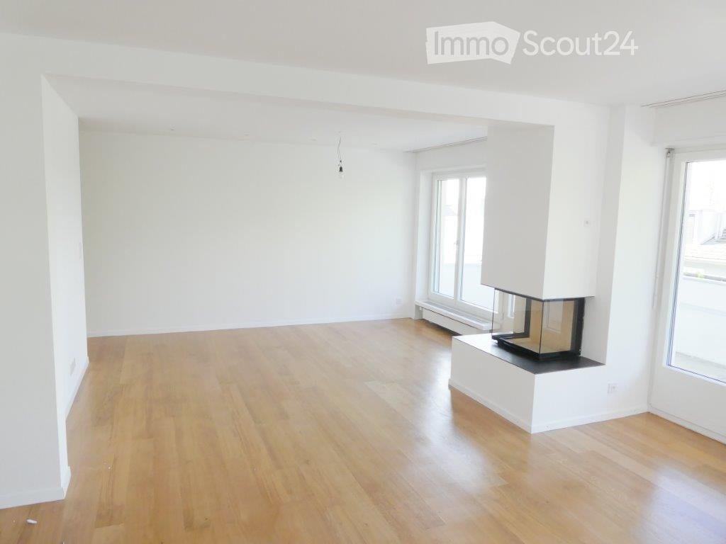 Empty room with light wooden flooring, white walls, and a built-in fireplace with a glass front.