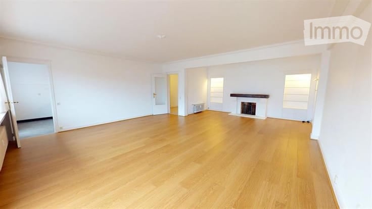 Empty room with light wooden flooring, white walls, and a fireplace. No furniture or equipment present.
