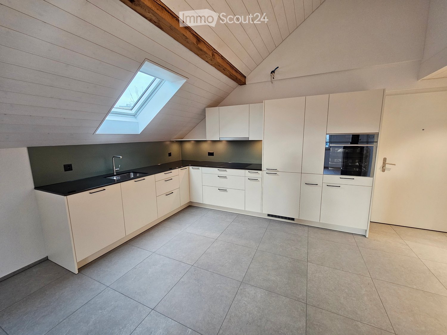 white kitchen cabinets, grey floor tiles, black countertops, stainless steel sink, dishwasher, built-in oven, skylight
