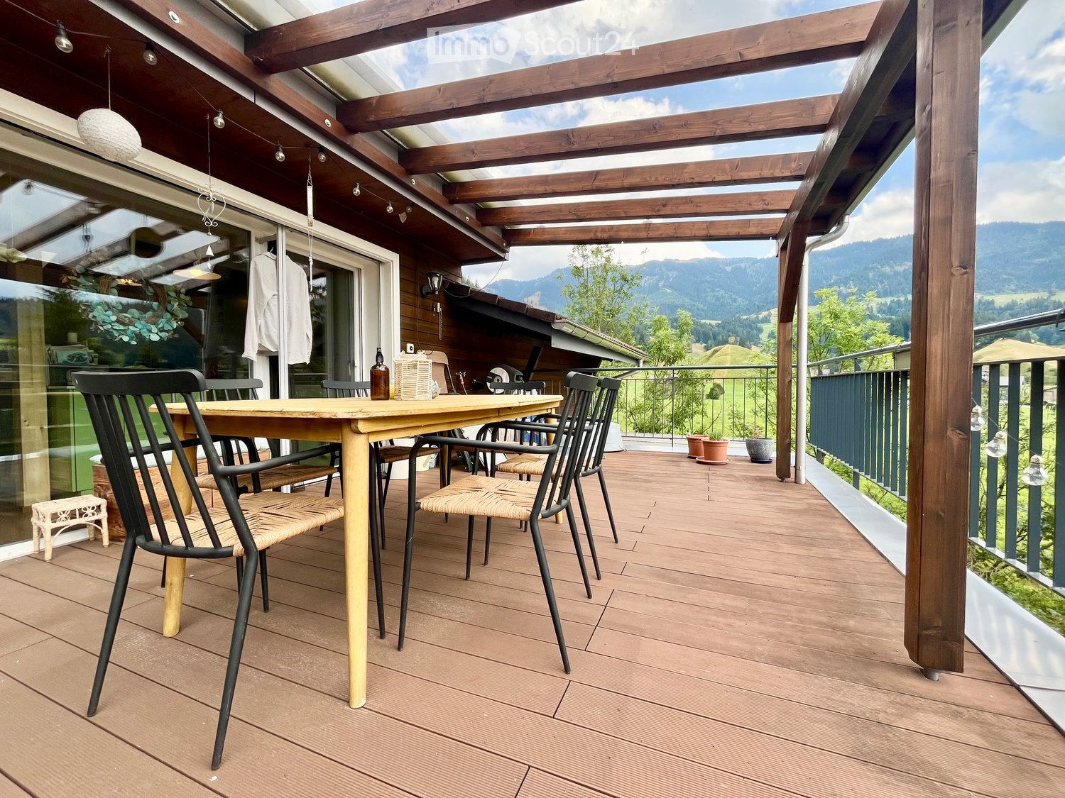 Wooden deck with a table and chairs, overlooking a scenic mountain view.