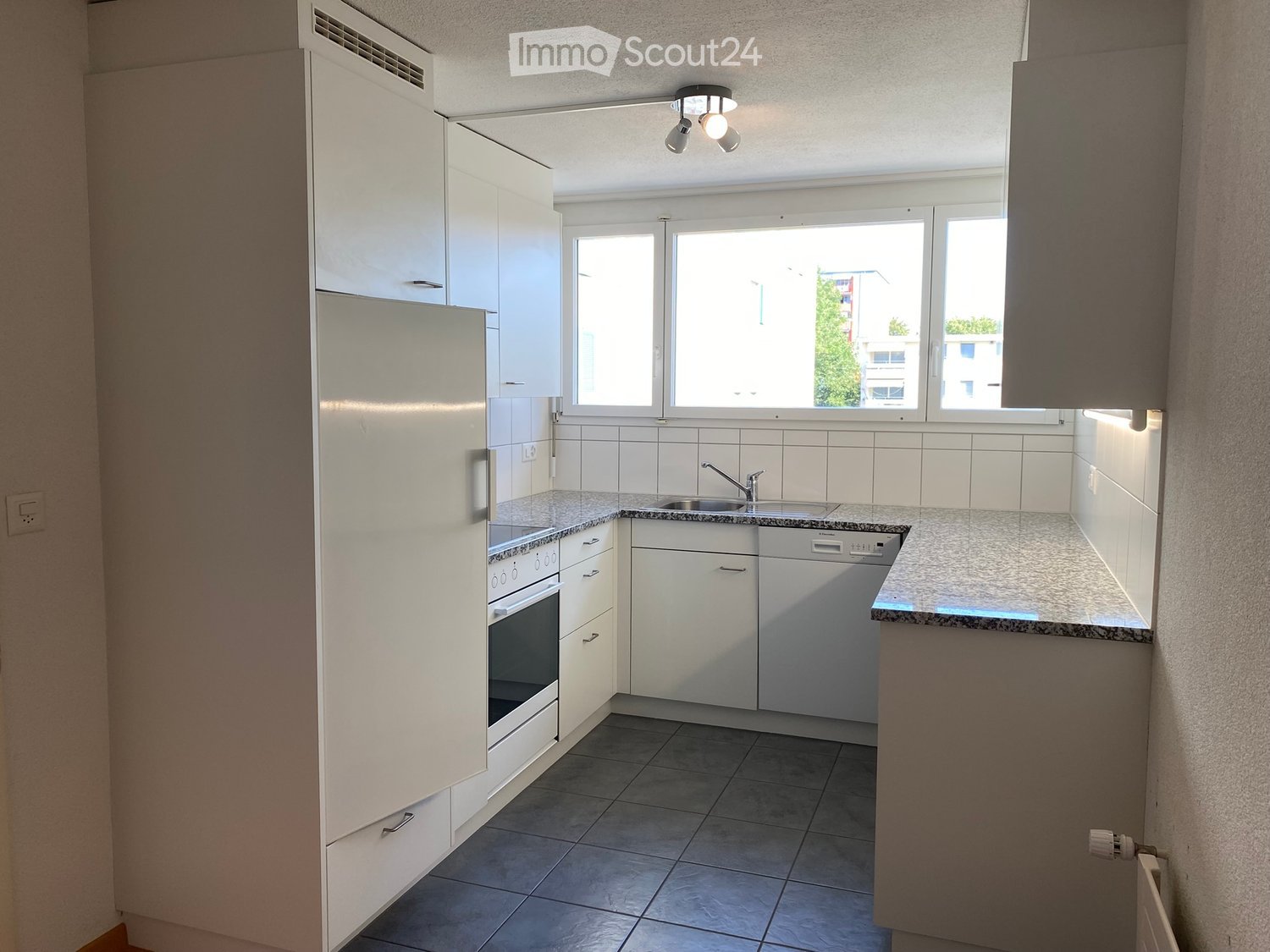 Modern kitchen with white cabinets, stainless steel appliances, granite countertops, and tiled flooring.