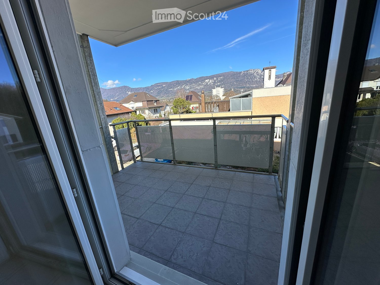 Balcony with tiled floor, metal railing, and scenic mountain view in the background.