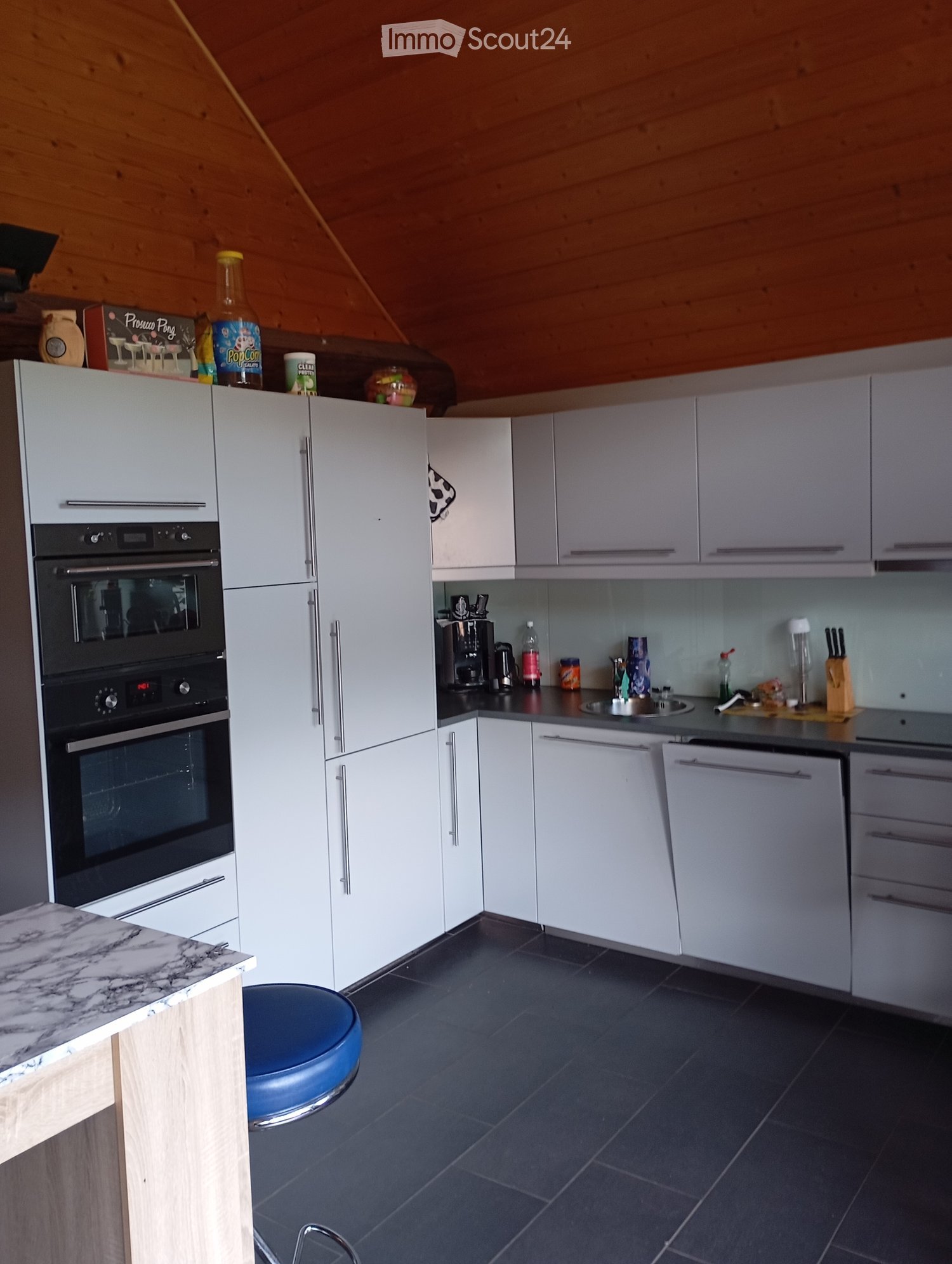 modern kitchen with white cabinets, black tiled floor, granite countertop, built-in oven, dishwasher, sink, and various kitchen appliances