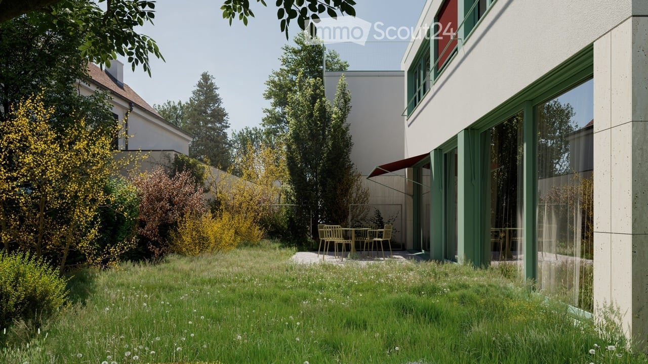 A modern garden area with a lawn, small trees, and a patio with outdoor furniture near a contemporary building.