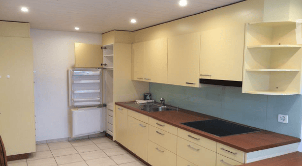 Modern kitchen with light-colored cabinets, a stainless steel sink, and a built-in stove. The refrigerator is open, revealing its interior.