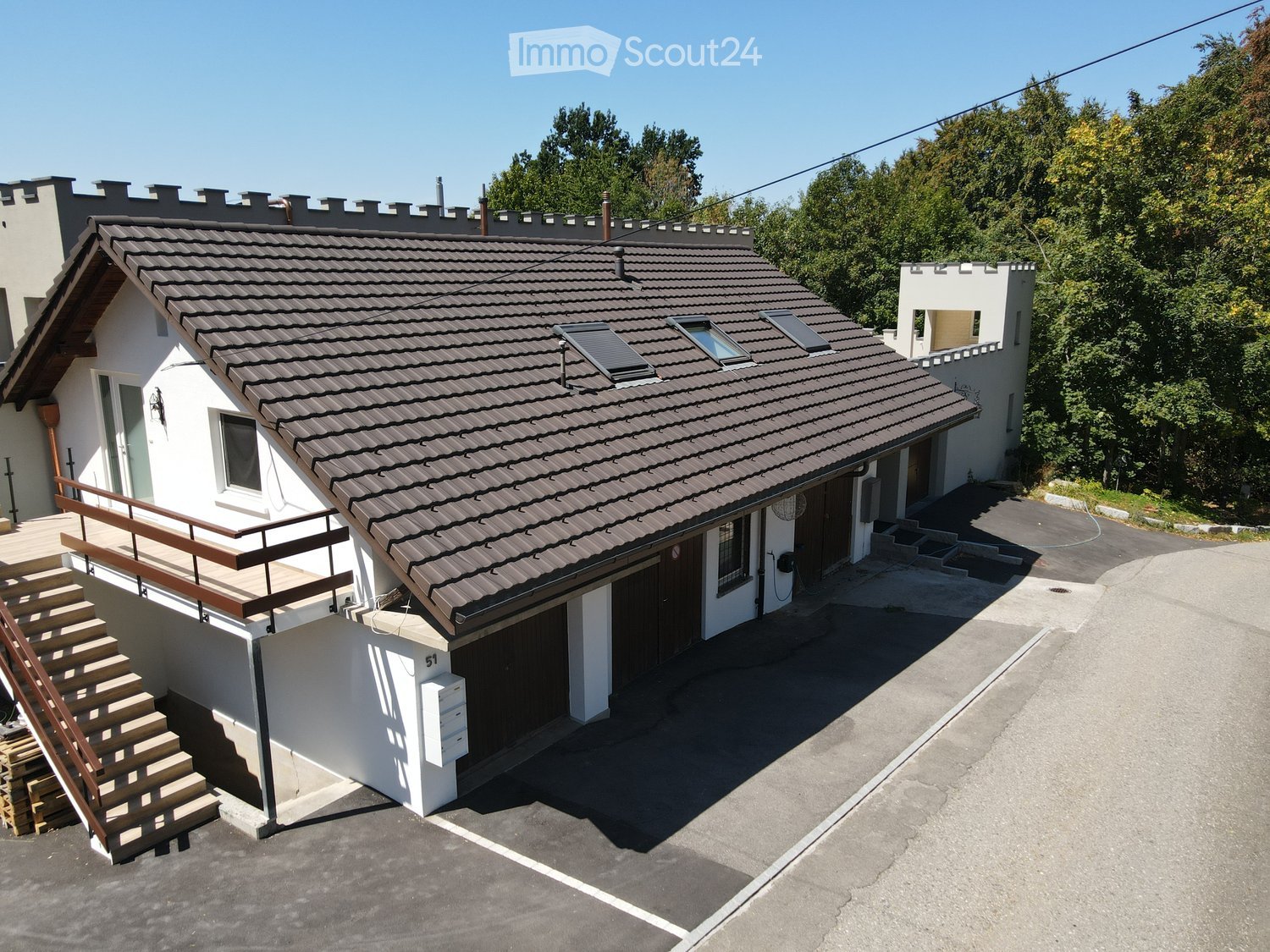 Two-story house with a tiled roof, white exterior, garage, and small balcony with wooden stairs.