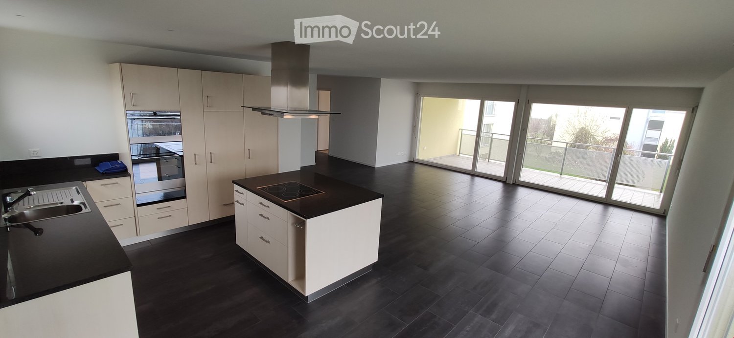 Modern kitchen with white cabinets, black countertops, induction cooktop, and large sliding glass doors leading to a balcony.