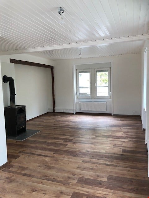 Empty room with wooden flooring, white walls, and a fireplace. No furniture or equipment present.