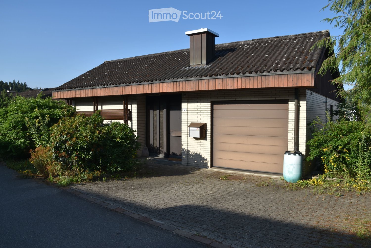 Two-story house with a tiled roof, garage, and a small garden area.