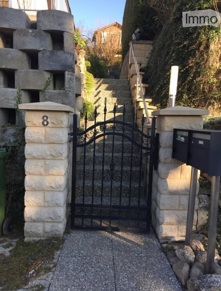 Stone entrance pillars, black wrought iron gate, stone walkway, metal handrails, stone steps, mailboxes on right, number 8 on left pillar.