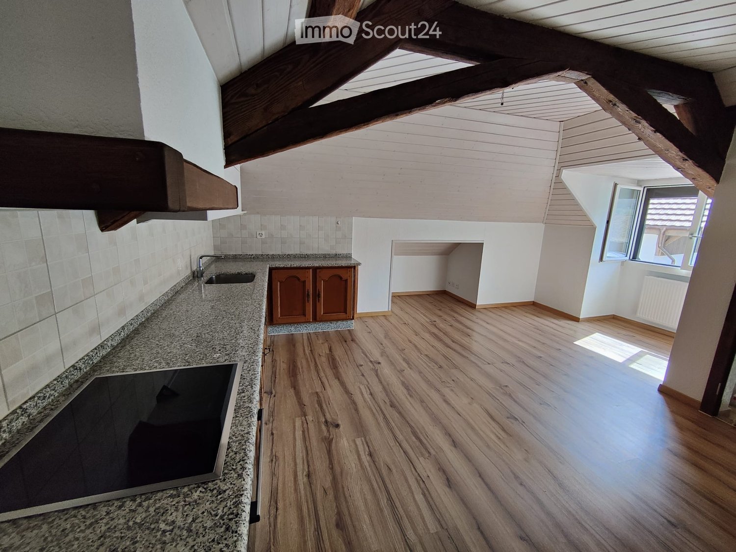 Modern kitchen with wooden flooring, granite countertop, sink, faucet, stove, and wooden cabinets.