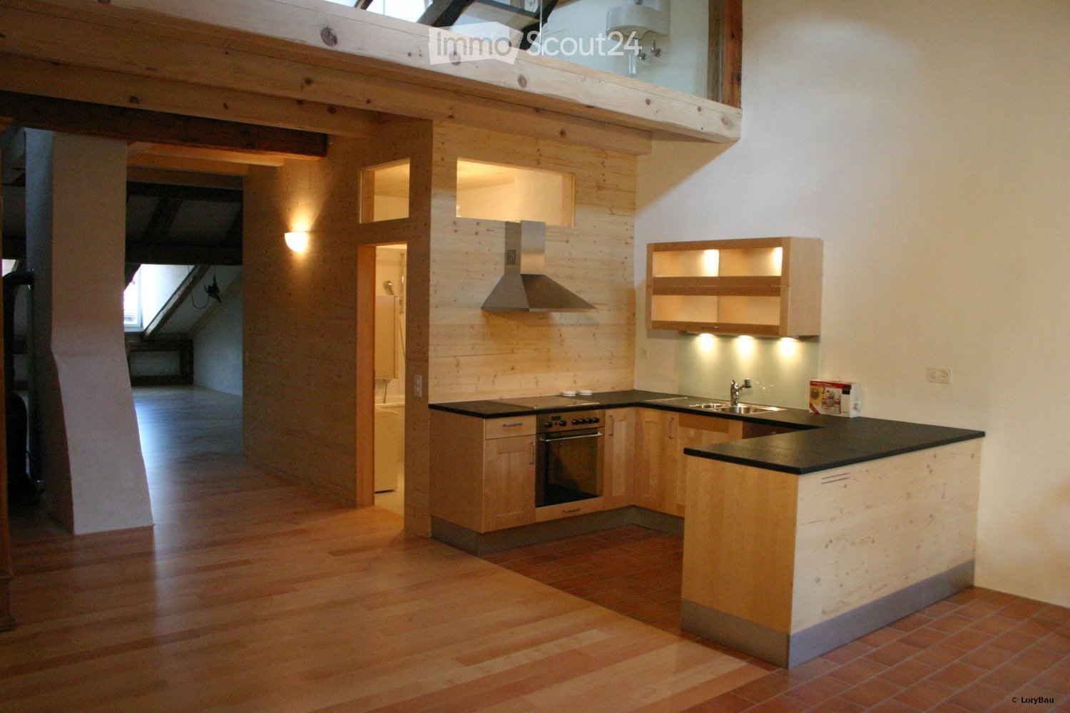 Modern kitchen with wooden cabinets, stainless steel appliances, and a black countertop. Features include a stove, oven, sink, range hood, and built-in lighting.