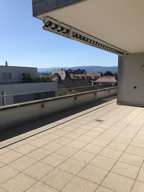 Balcony with tiled floor, metal railing, and a view of the city and surrounding hills.