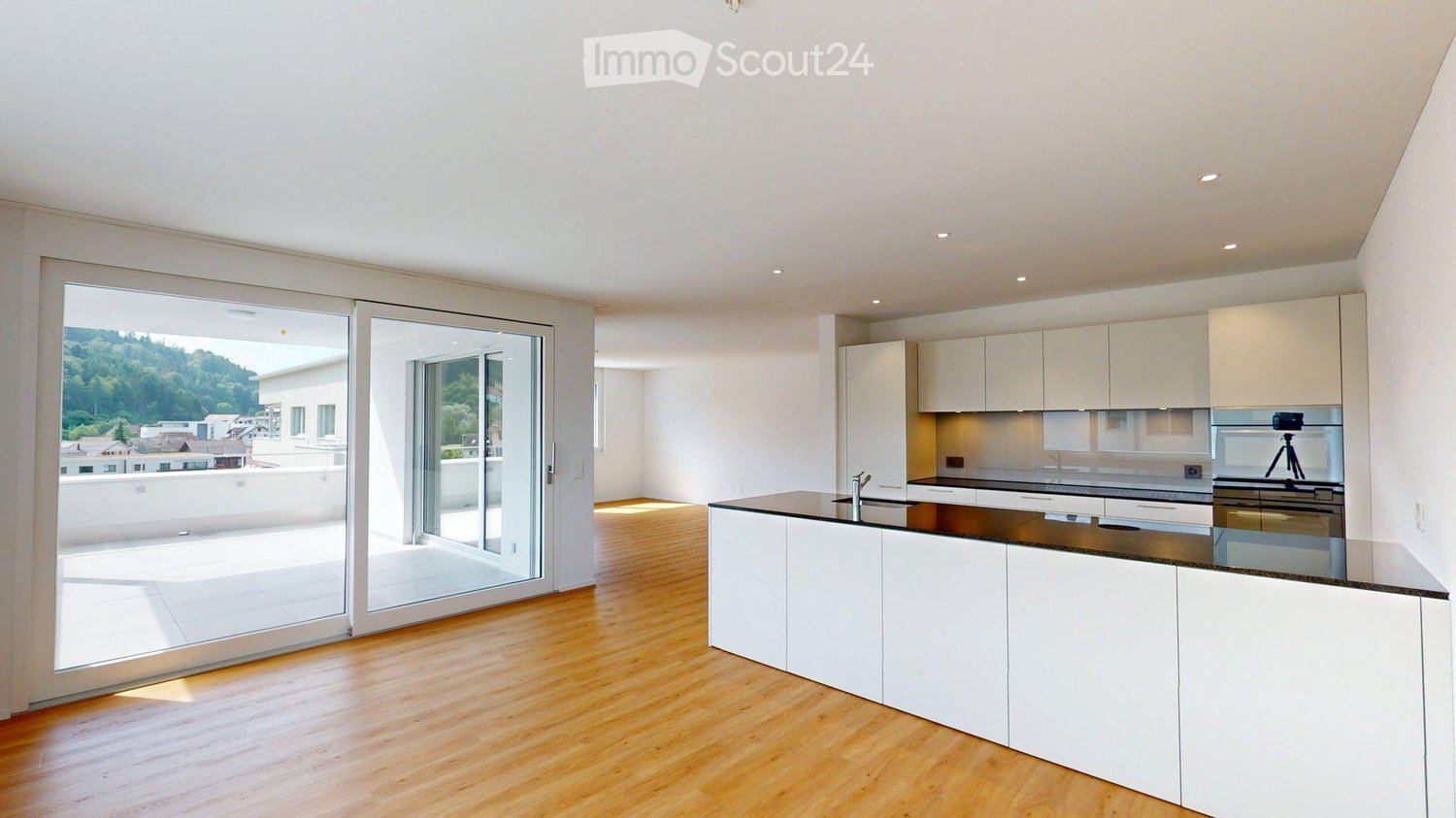 Modern kitchen with white cabinets, a central island, and large sliding glass doors leading to a balcony.