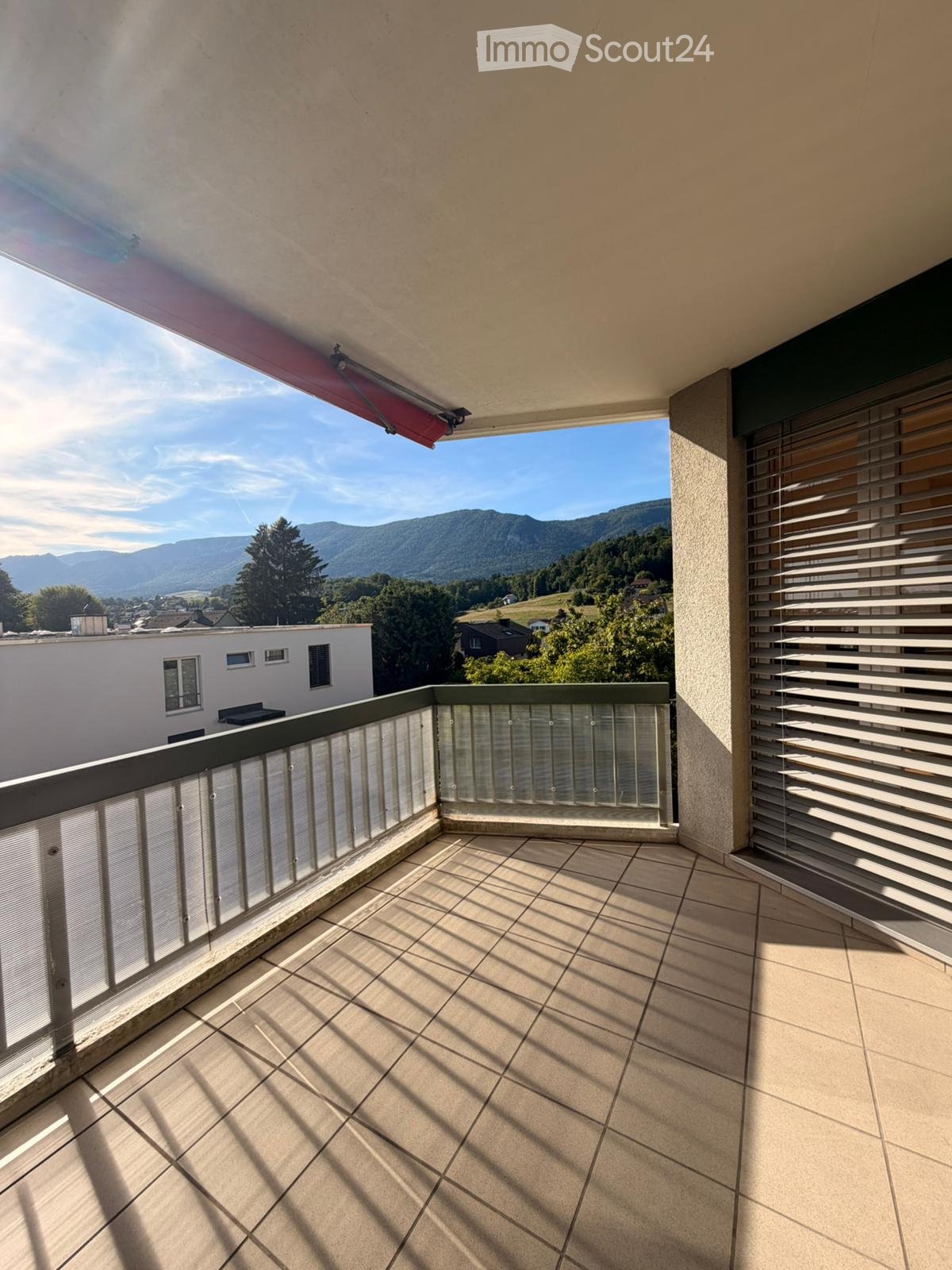 Balcony with tiled floor, glass railing, and scenic mountain view.