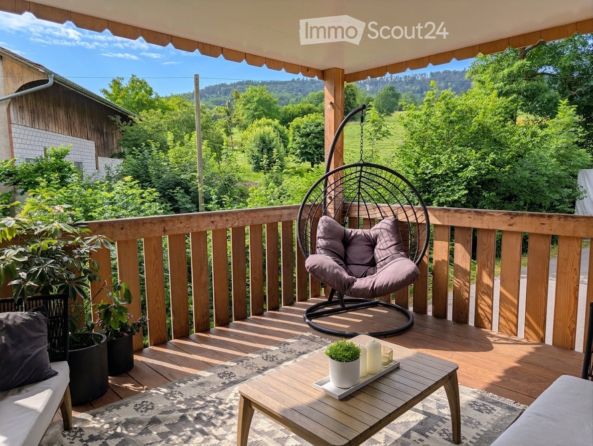 Wooden balcony with a hanging wicker chair, small wooden coffee table, potted plants, and scenic countryside view.