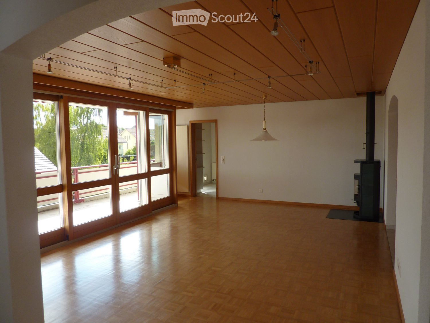 Empty room with wooden floors, sliding glass doors, fireplace, wooden ceiling