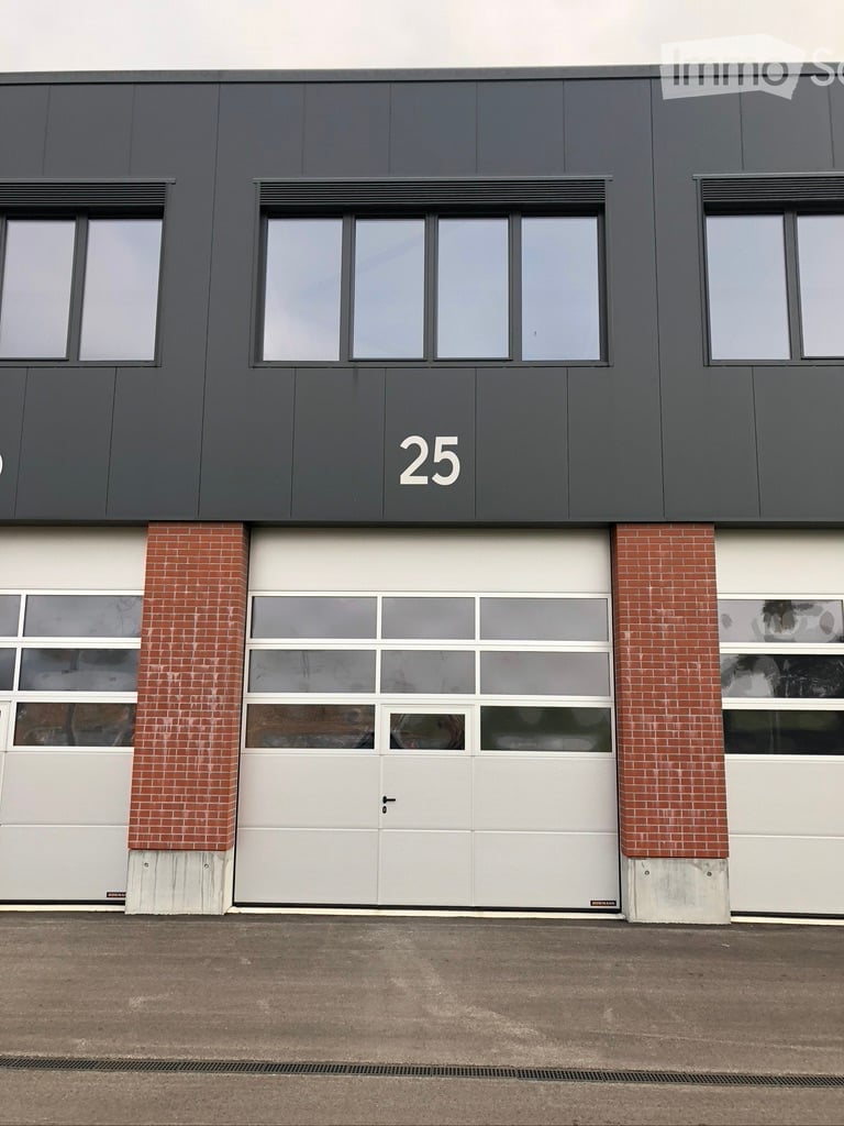 Modern industrial-style building with a large garage door, brick columns, and numbered '25' on the facade.