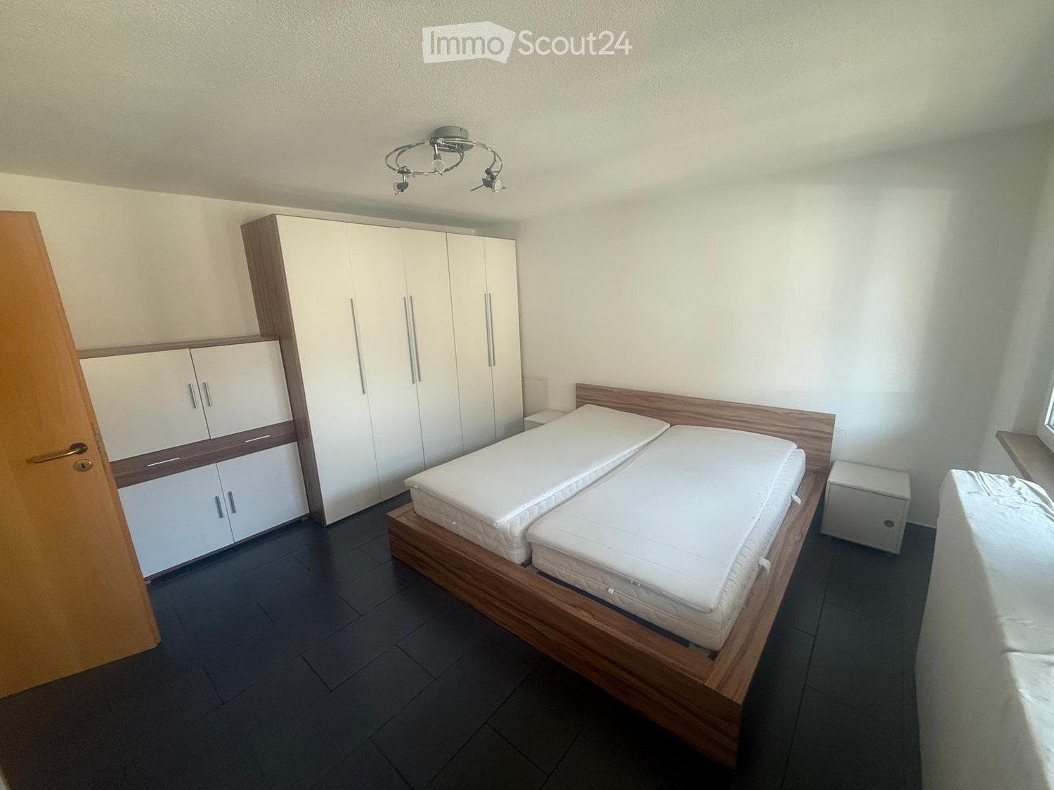Modern bedroom with a double bed, white mattresses, built-in wardrobes, and a nightstand.