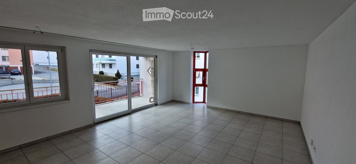 Empty room with tiled floor, white walls, large window, and sliding glass door leading to a balcony area.