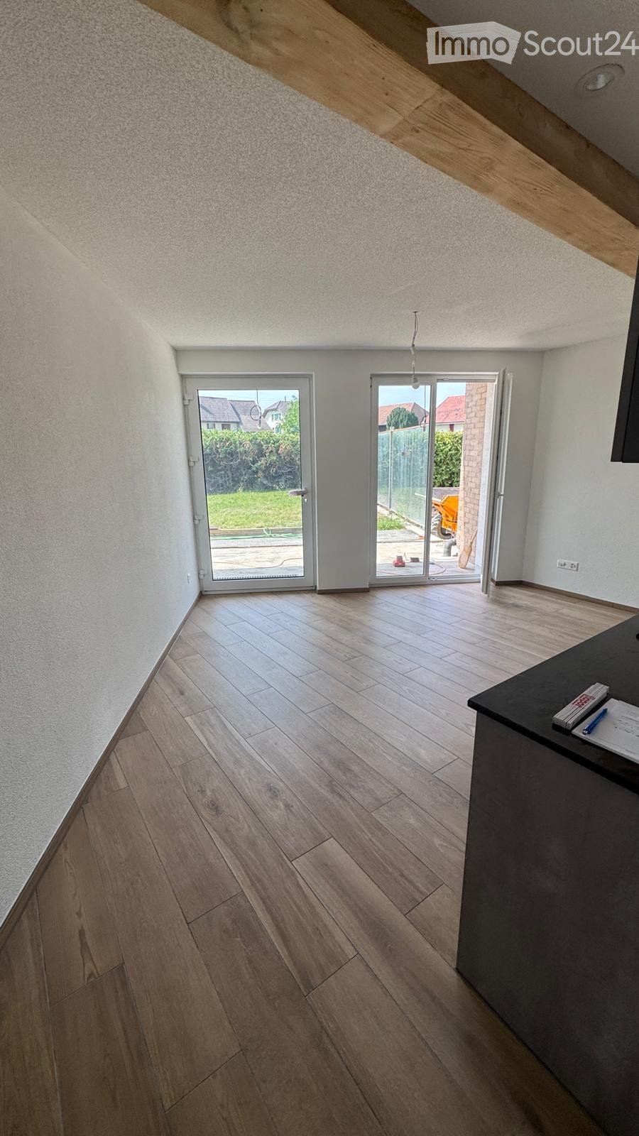 Empty room with wooden flooring, white walls, and large sliding glass doors leading to an outdoor area.