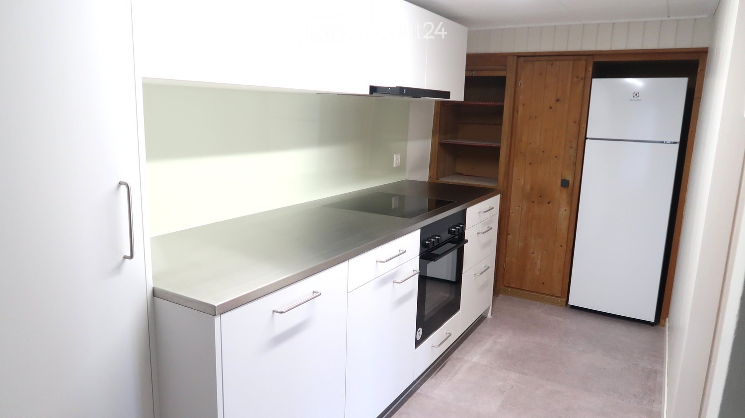 Modern kitchen with white cabinets, stainless steel appliances, and a wooden pantry door.