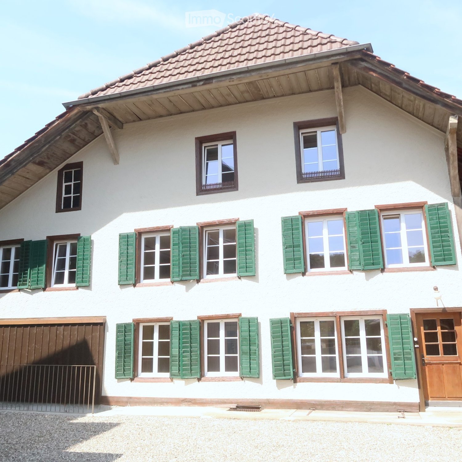 2-story building, white walls, red roof, brown trim, wooden garage door, brown front door, 13 windows with green shutters