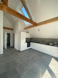Modern kitchen with white cabinets, stainless steel appliances, and a large skylight above the sink.