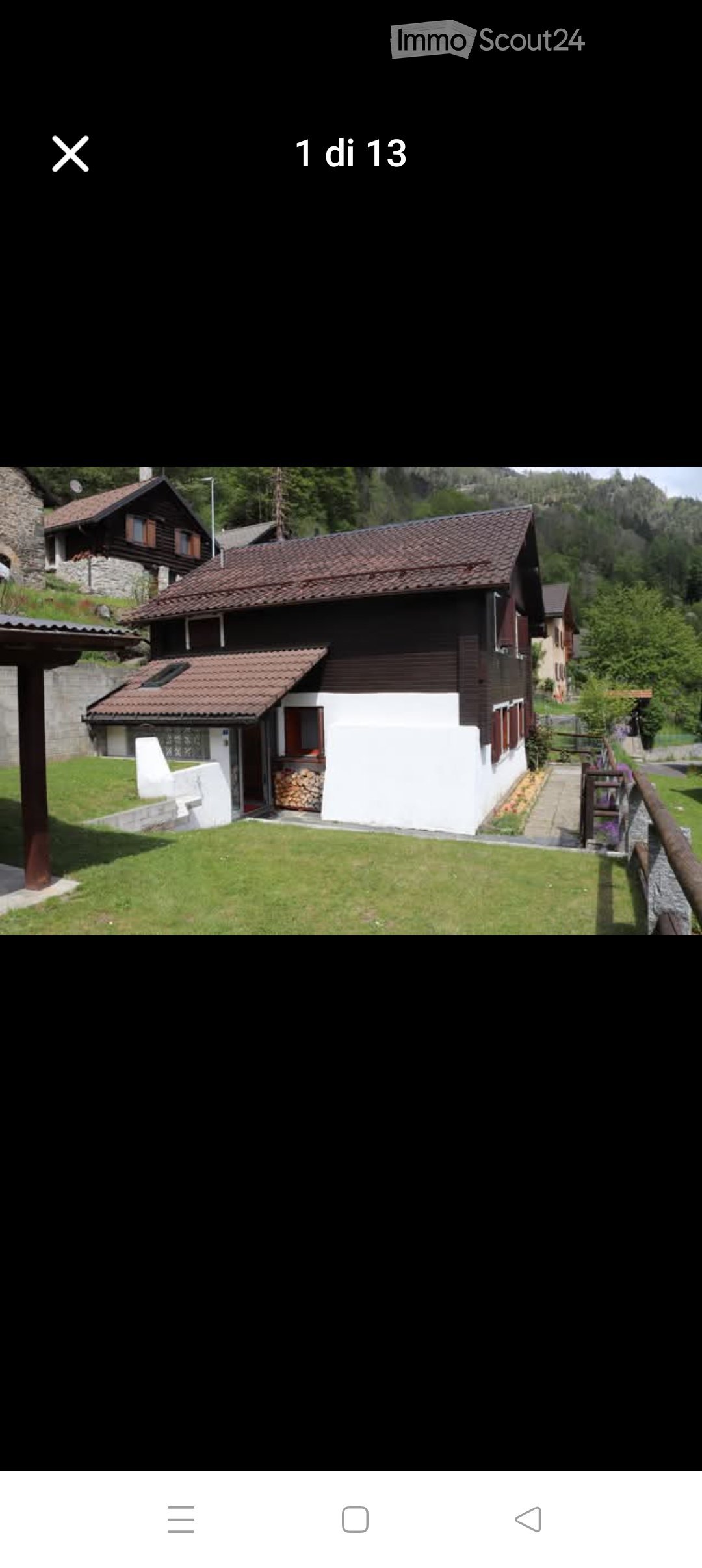 A two-story house with a red-tiled roof, white and dark wooden exterior, surrounded by a well-maintained lawn and garden area.