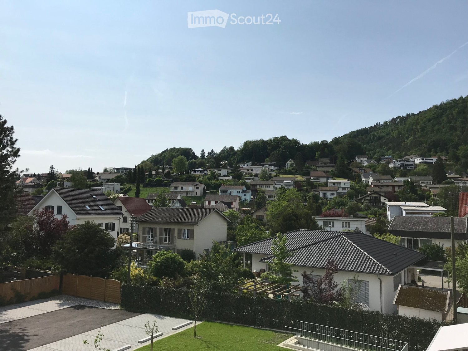 Residential neighborhood with multiple houses, surrounded by greenery and trees, with a clear view of the surrounding landscape.
