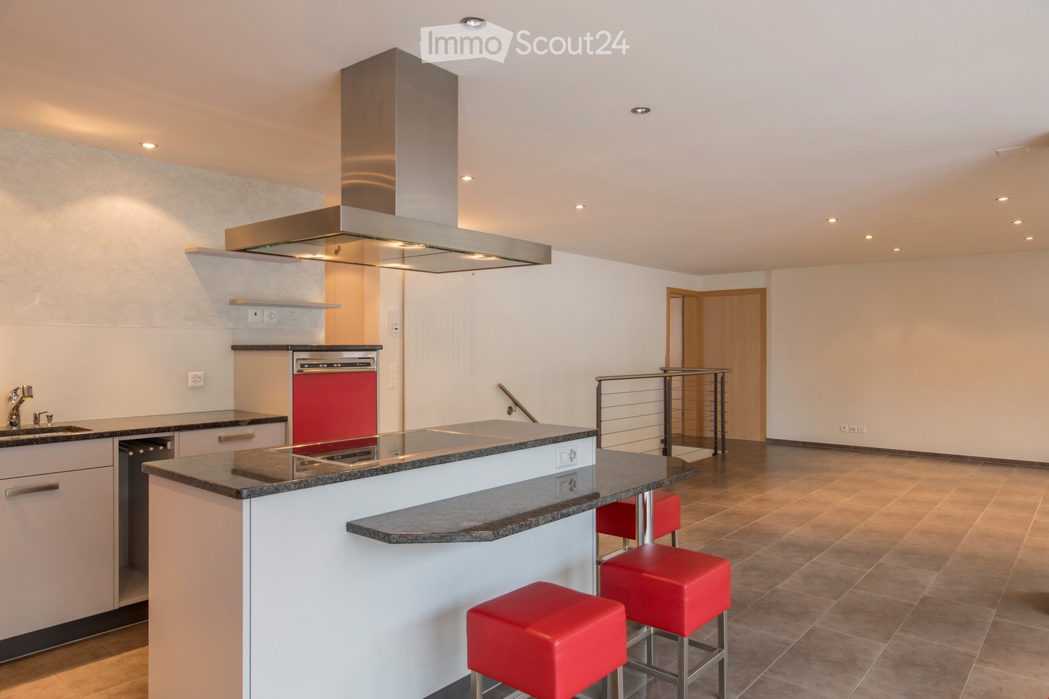 Modern kitchen with white cabinets, granite countertops, stainless steel range hood, and red stools at the island.