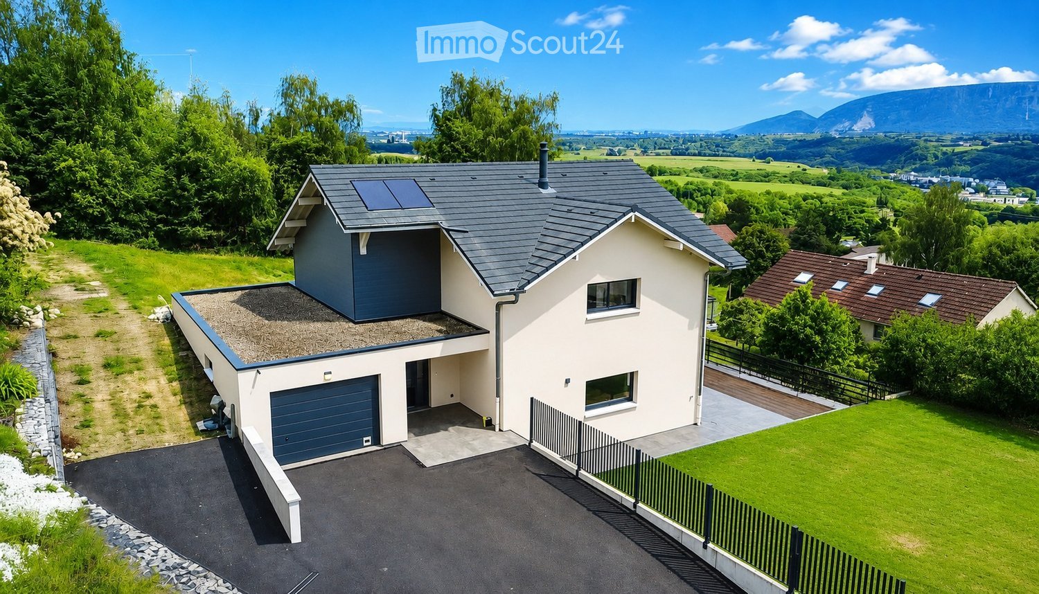 Modern two-story house with grey roof, white walls, garage, and solar panels on the roof. Surrounded by green lawn and trees with a scenic mountain view in the background.