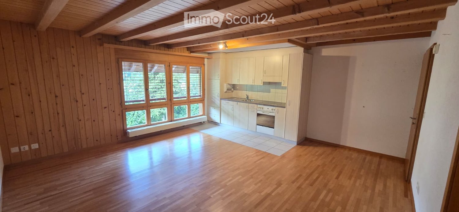 Bright, open kitchen with white cabinets, stainless steel appliances, and large windows. The space features wooden walls and a polished wooden floor.
