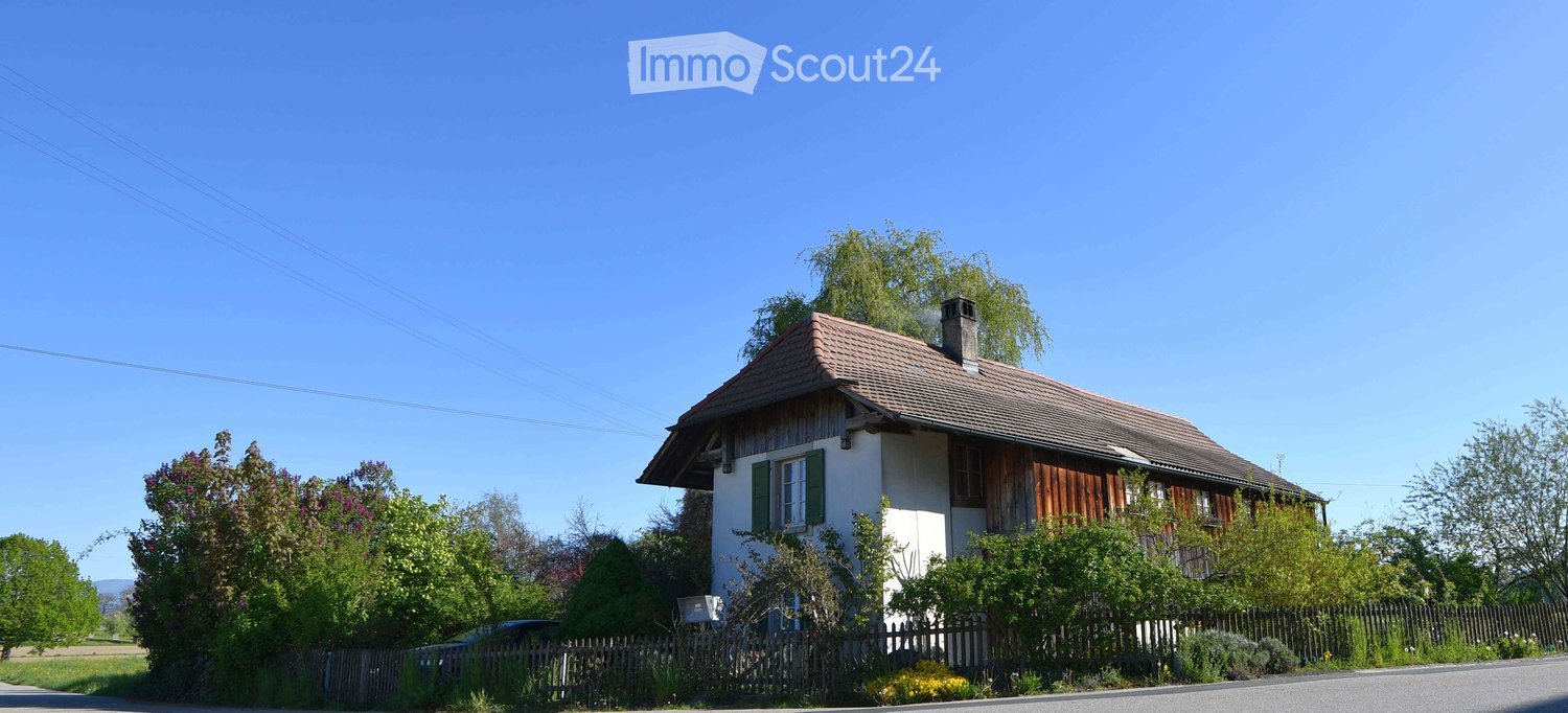 2 story house, brown roof, white walls, wooden exterior, chimney, surrounded by trees and plants