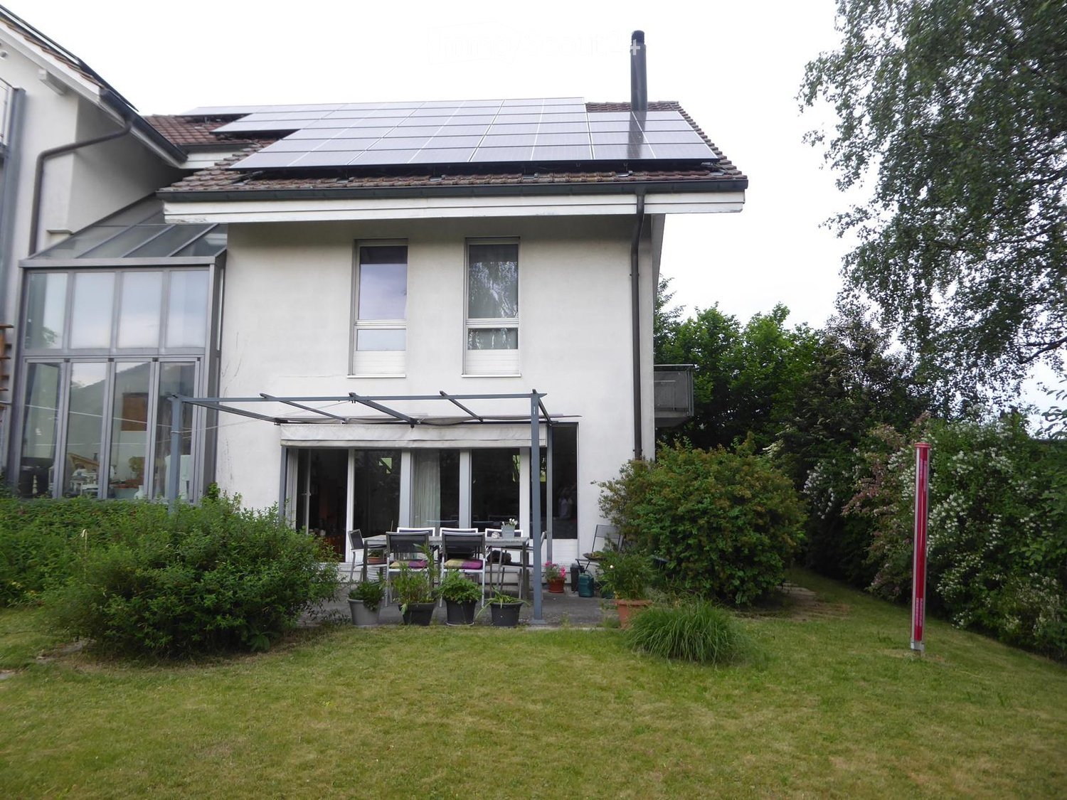 Well-maintained garden with a patio area, outdoor furniture, and potted plants near the house.