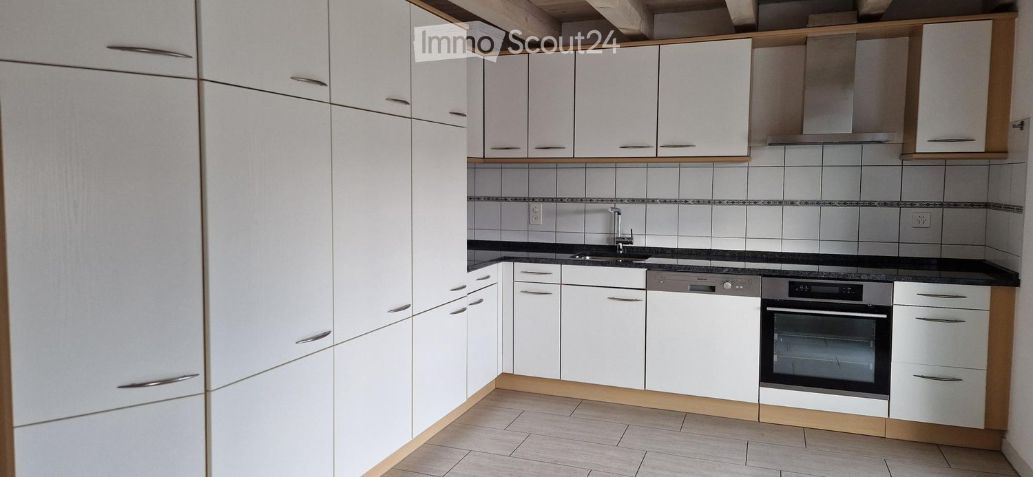 Modern kitchen with white cabinets, stainless steel appliances, and a black countertop.