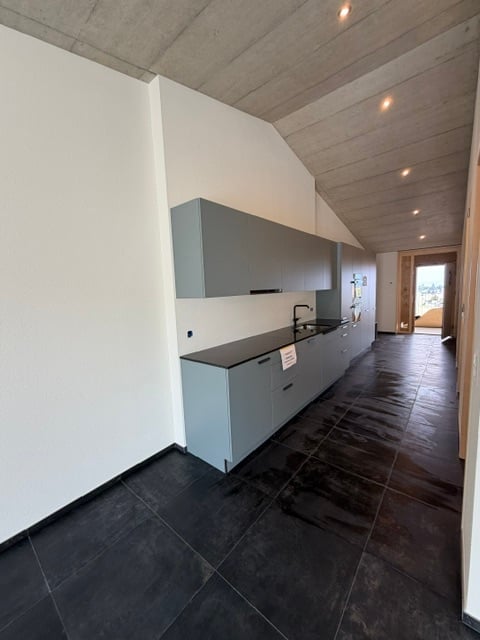 Modern kitchen with grey cabinets, black tiled floor, and a sleek sink area.