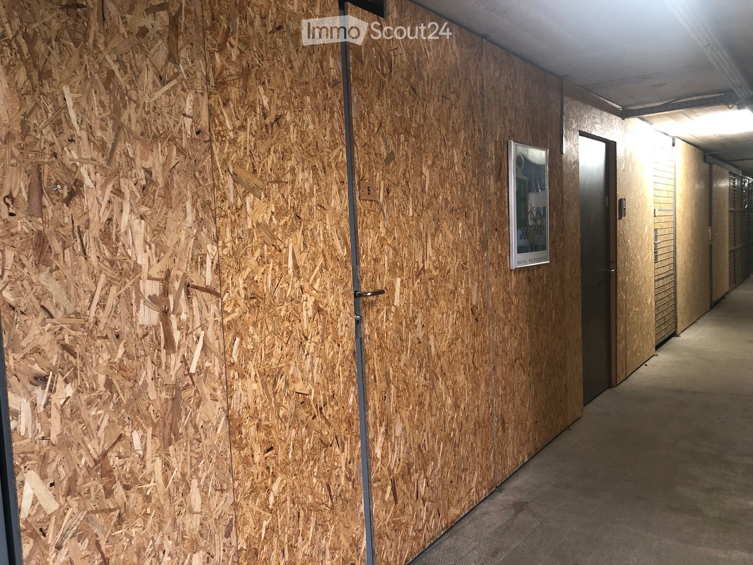 A modern hallway with wooden panel walls, a door, and a sign on the wall.