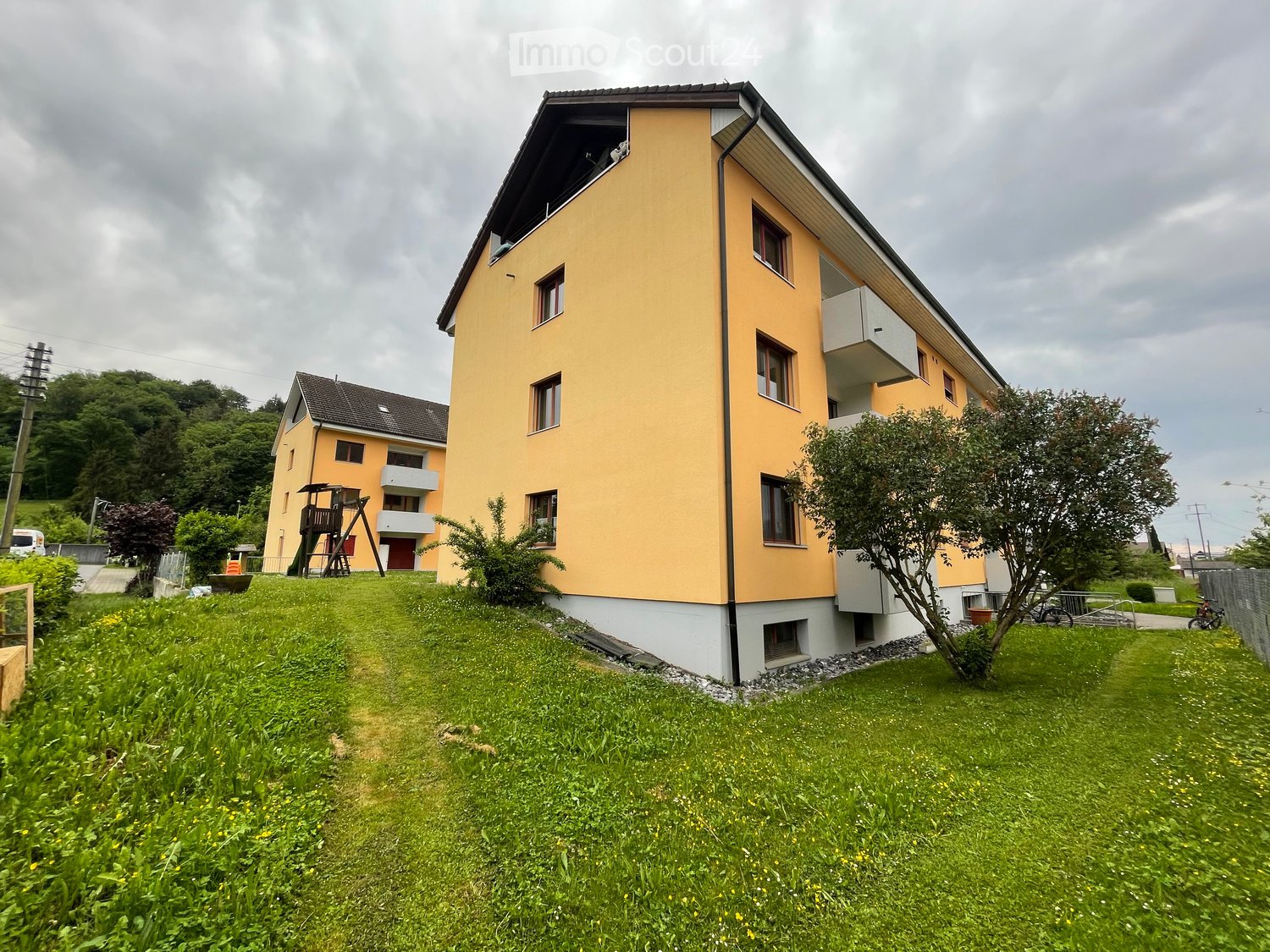 2 story yellow house, white trim, multiple balconies, large grassy yard