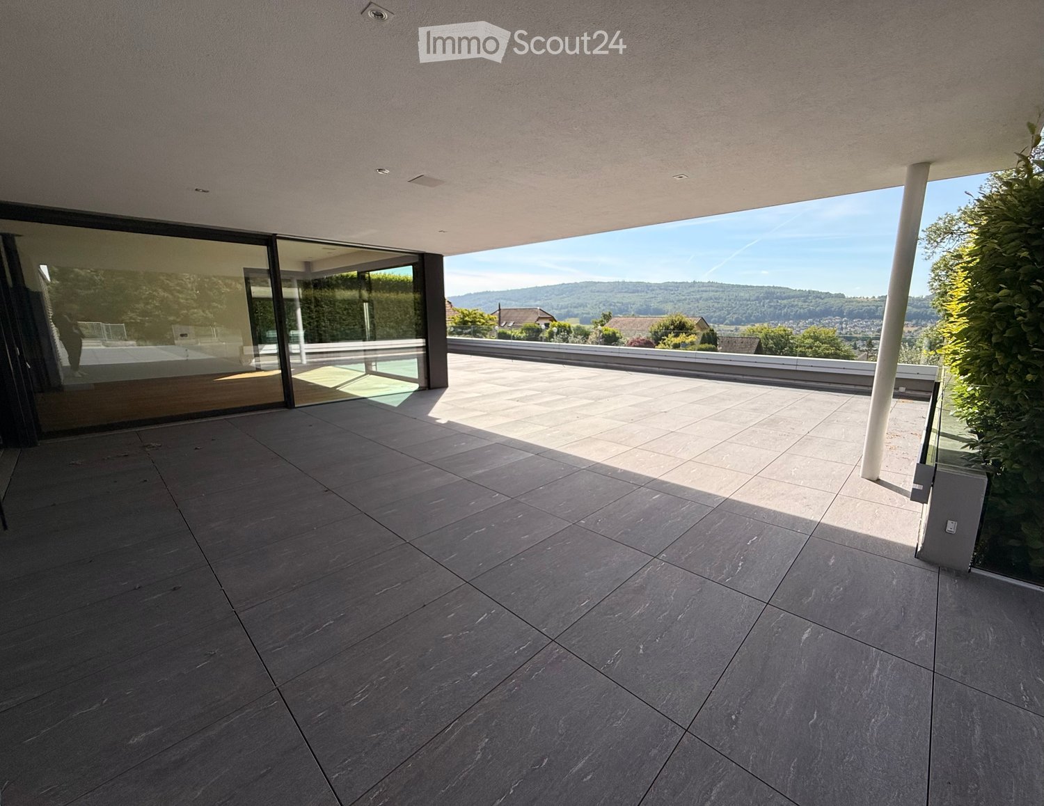 Modern balcony with large glass sliding doors, tiled floor, and scenic mountain view.