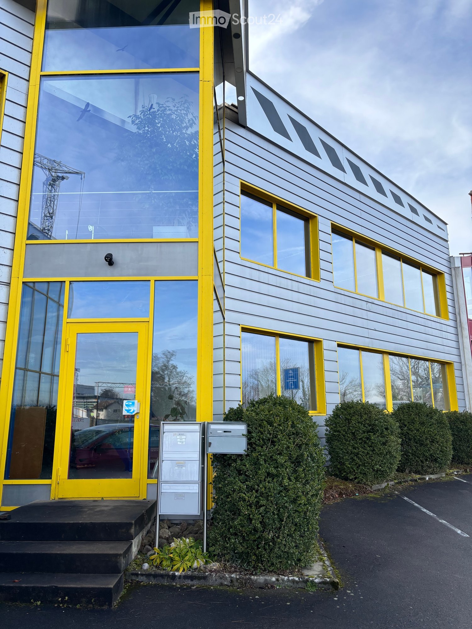 yellow-framed building with glass windows, parking in front, a yellow door