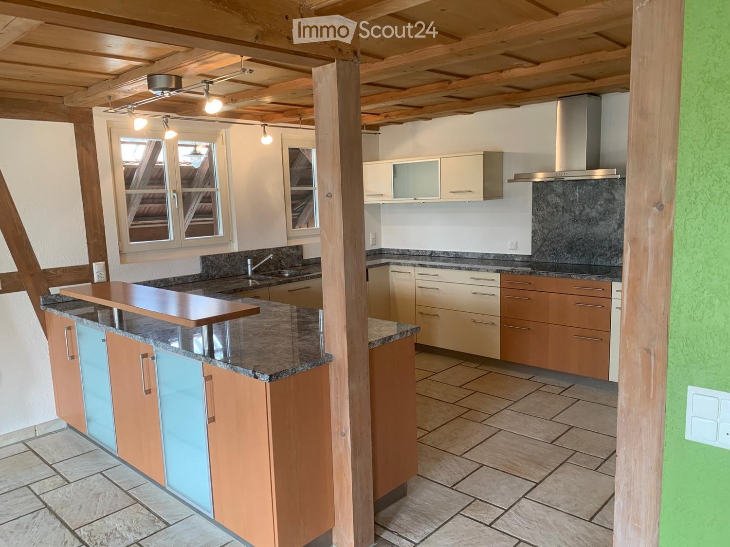 Modern kitchen with wooden cabinets, granite countertops, and stainless steel appliances. Features a central island with a wooden breakfast bar and ample storage space.