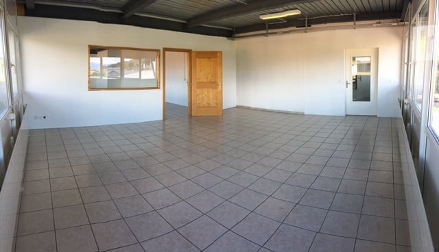 Empty room with tiled floor, white walls, and wooden doors. No furniture or equipment present.