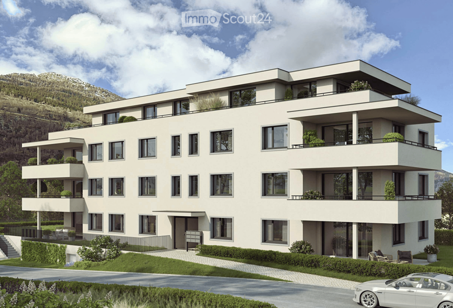 Modern multi-story residential building with white facade, large windows, balconies, and surrounding greenery.